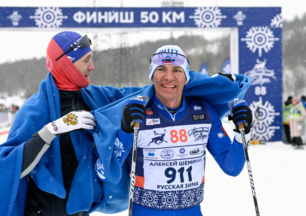 Почетный гость соревнований олимпийский чемпион, трехкратный чемпион мира по лыжным гонкам Никита Крюков укутывает на финише в фирменный плед победителя 50-километровой гонки классическим стилем Алексея Шемякина из "Русской Зимы".